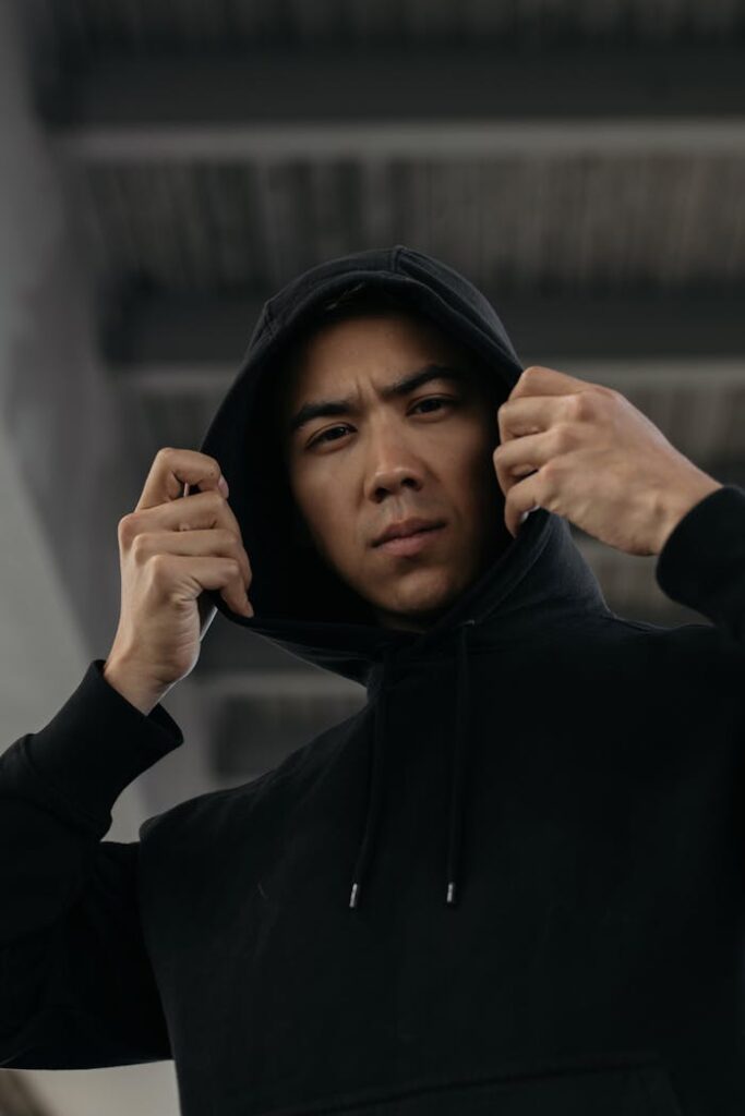 Crafting Captivating Headlines: Your awesome post title goes here Young Asian man in a black hoodie indoors, captured in a contemplative pose.